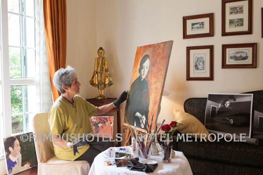 Joan Baez entering a new career: she is painting a portrait at her suite at the Hotel Metropole. Later, she donated that painting to the hotel.